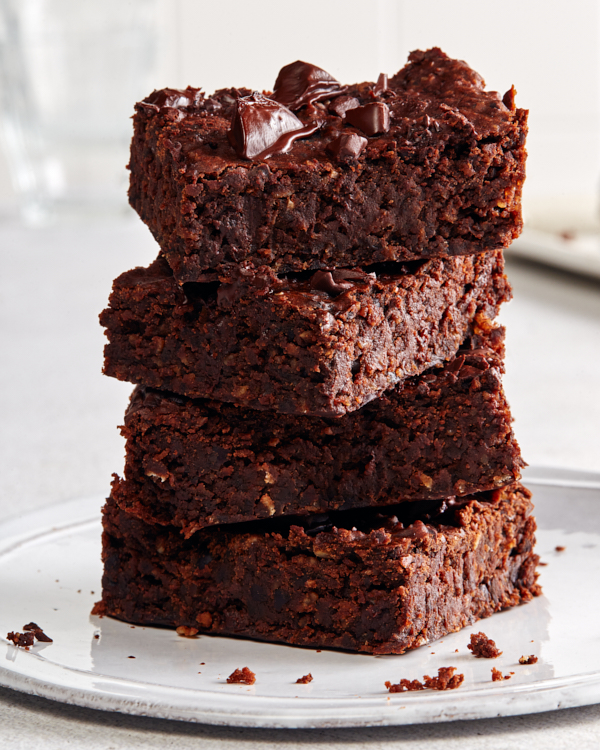 Une empilade de quatre brownies au chocolat végétaliens sur une assiette blanche.